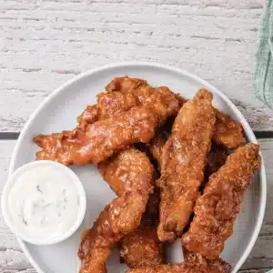 A plate of buffalo chicken tenders with a cup of ranch dip