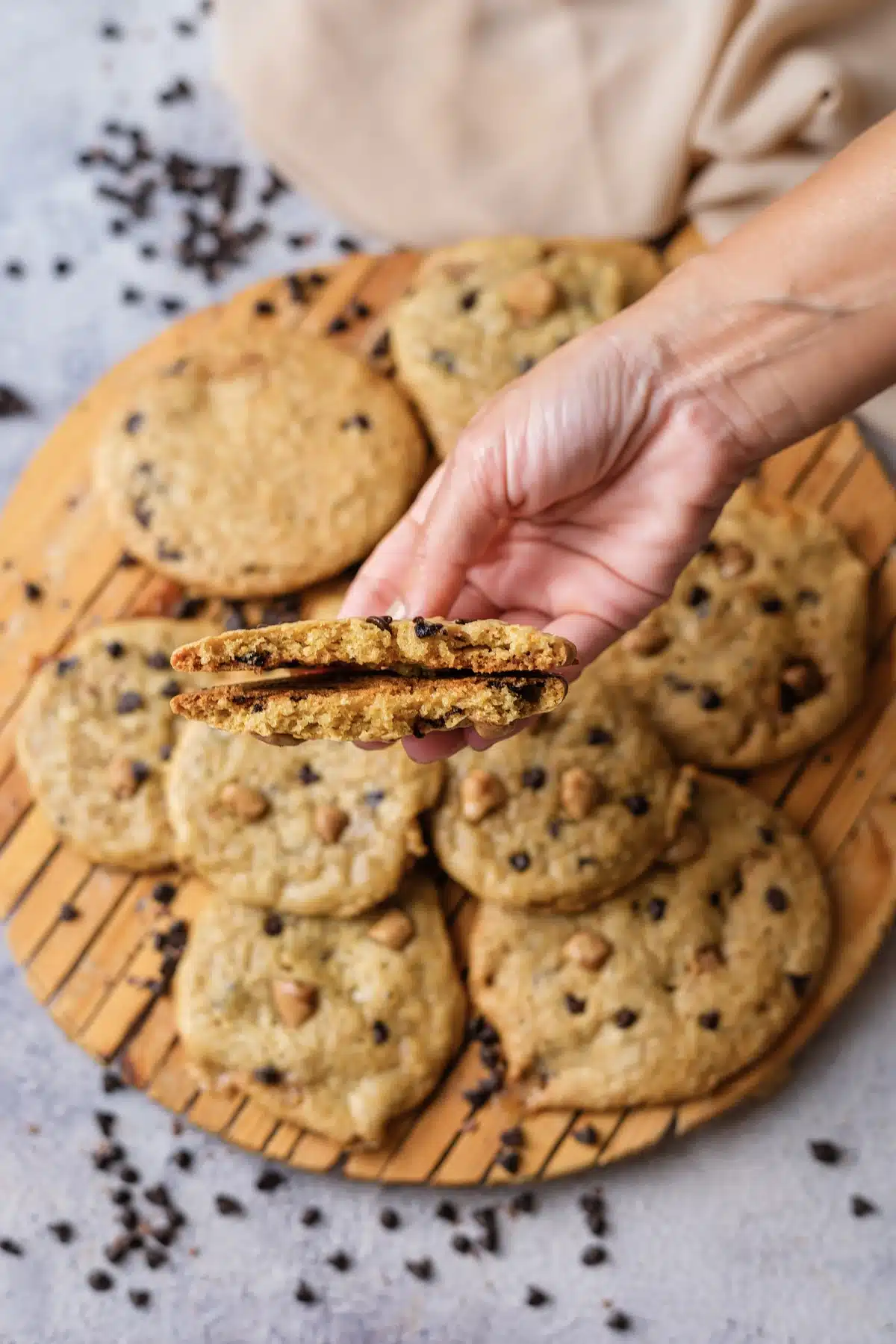 A hand holding a cookie snapped in half over the board to show the soft center
