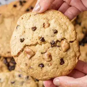 A single butterscotch chocolate chip cookie held up in two hands