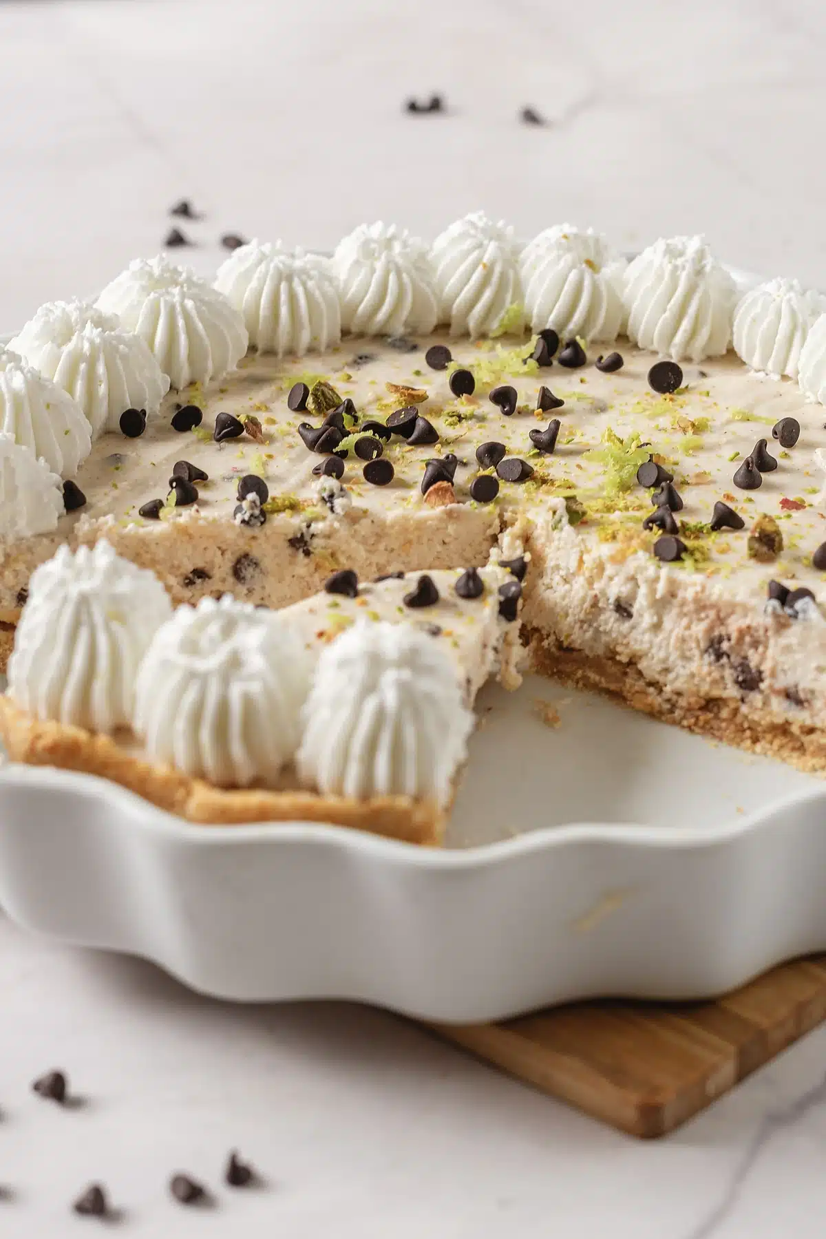Cannoli pie on a board seen from the side with the piped cream border