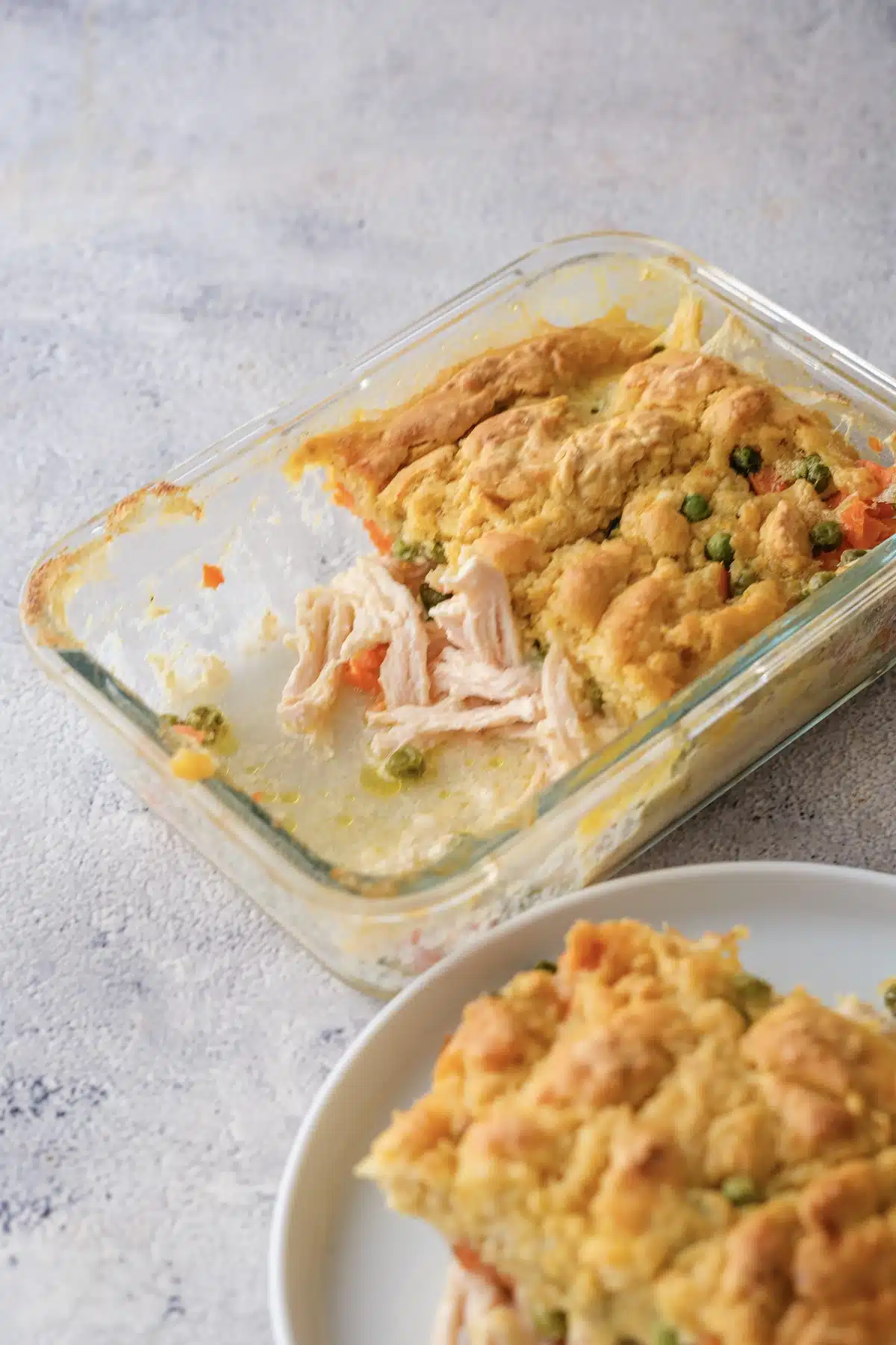 A square of Red Lobster chicken cobbler lifted from the corner of the glass dish, with a plated piece in front