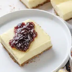 A single square of chilled cheesecake on a white plate