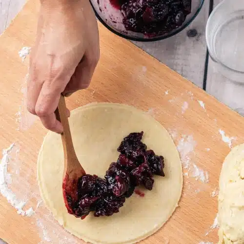 Dark cherry filling spooned onto the center of a pastry round
