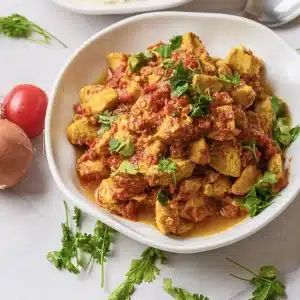 A single plate of chicken tikka masala in a thick tomato sauce with cilantro