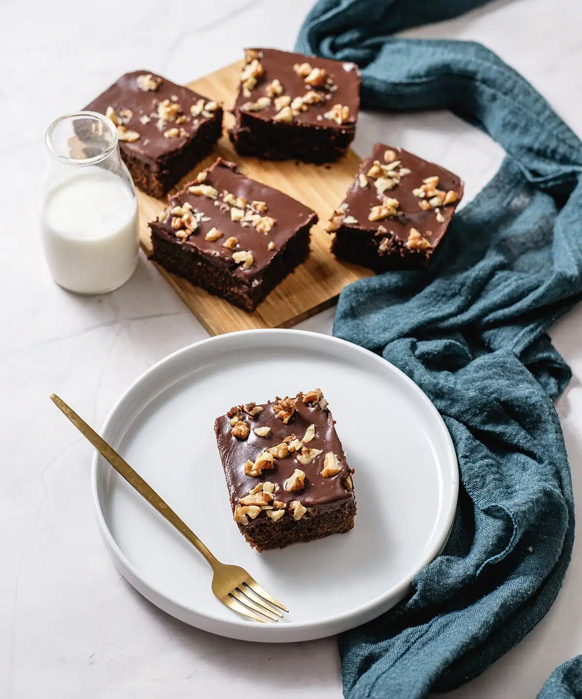 Chocolate buttermilk cake on a board with a single square plated alongside