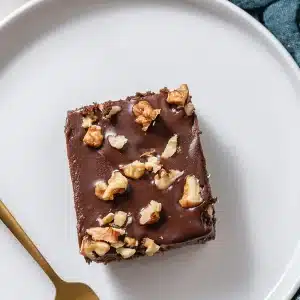 A single frosted square on a white plate with a gold fork