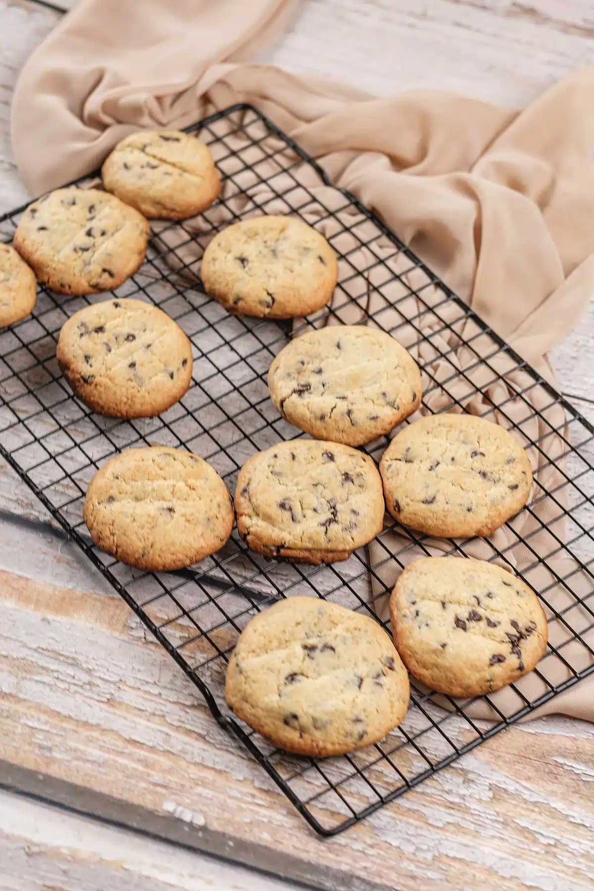 Chocolate chip pudding cookies cooling on a wire rack with a beige cloth behind