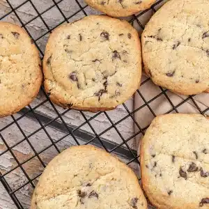 One thick chocolate chip pudding cookie on a black wire rack