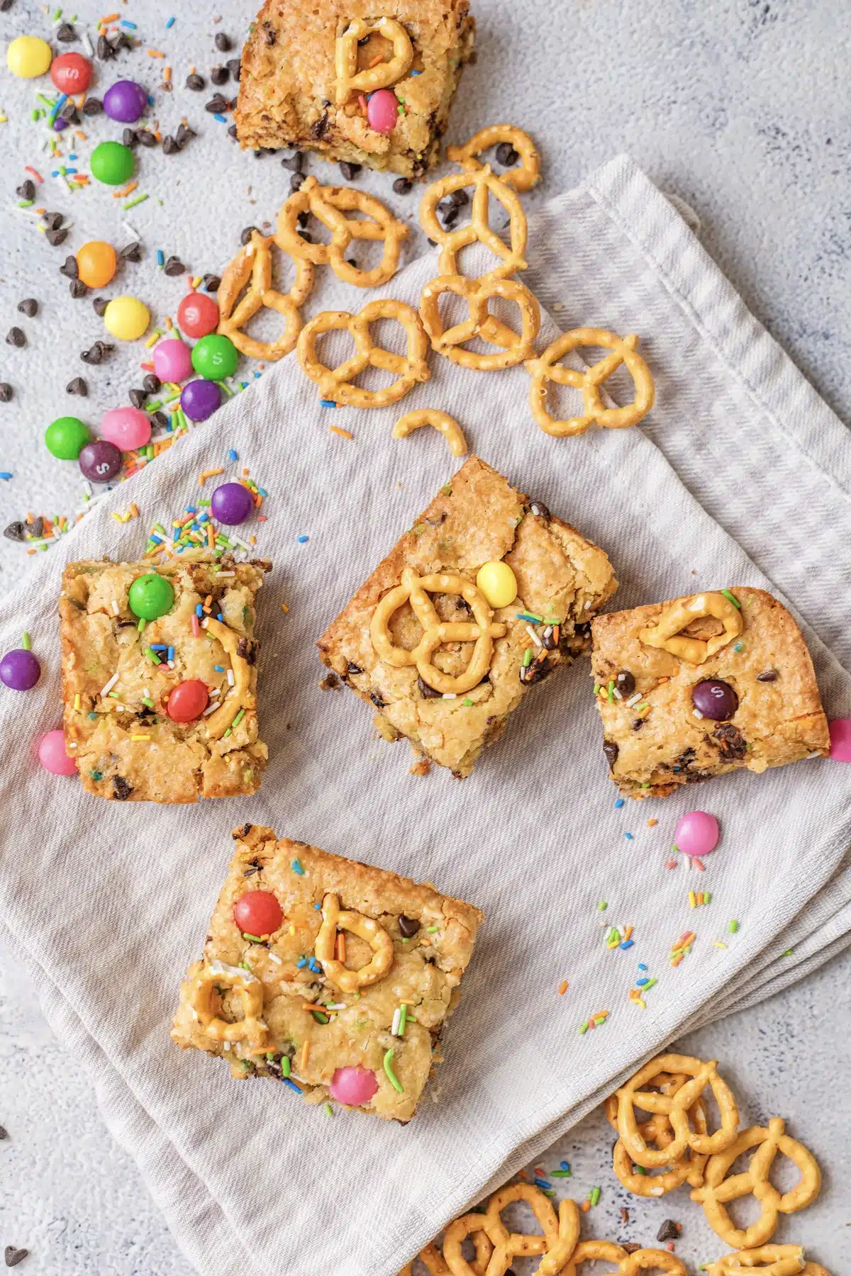 Four Christmas cookie bars, rainbow version, cut into squares on a striped cloth, seen from above
