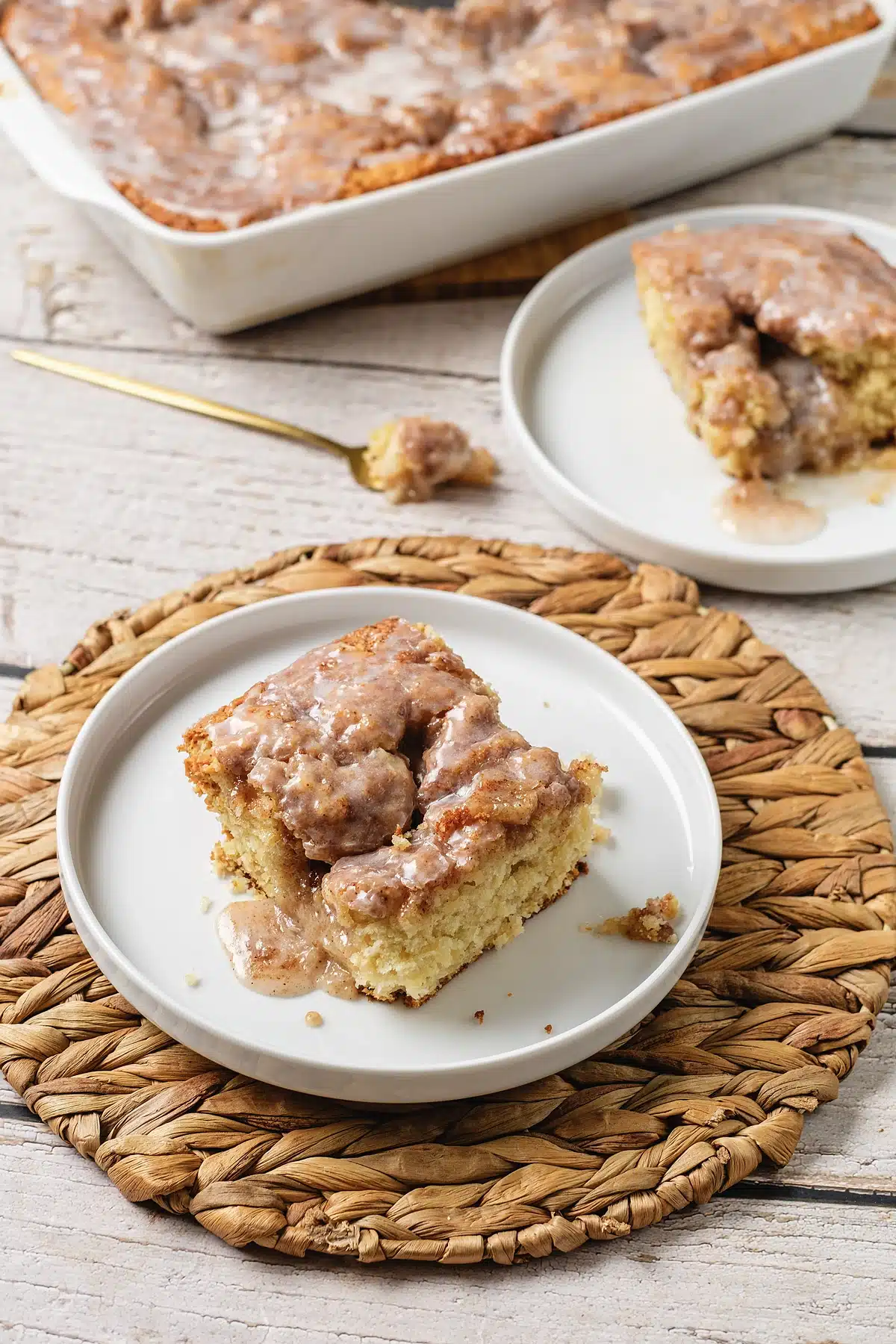 Cinnamon roll coffee cake on a woven mat with the pan behind