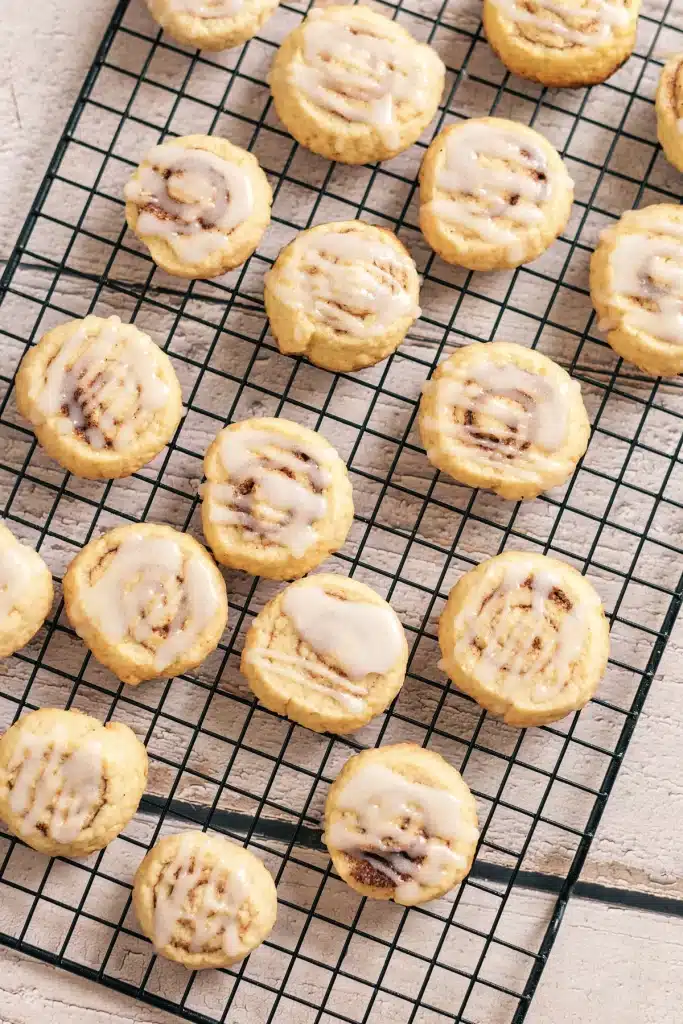 Cinnamon roll cookies on a wire rack seen from directly above, each with a glazed spiral top