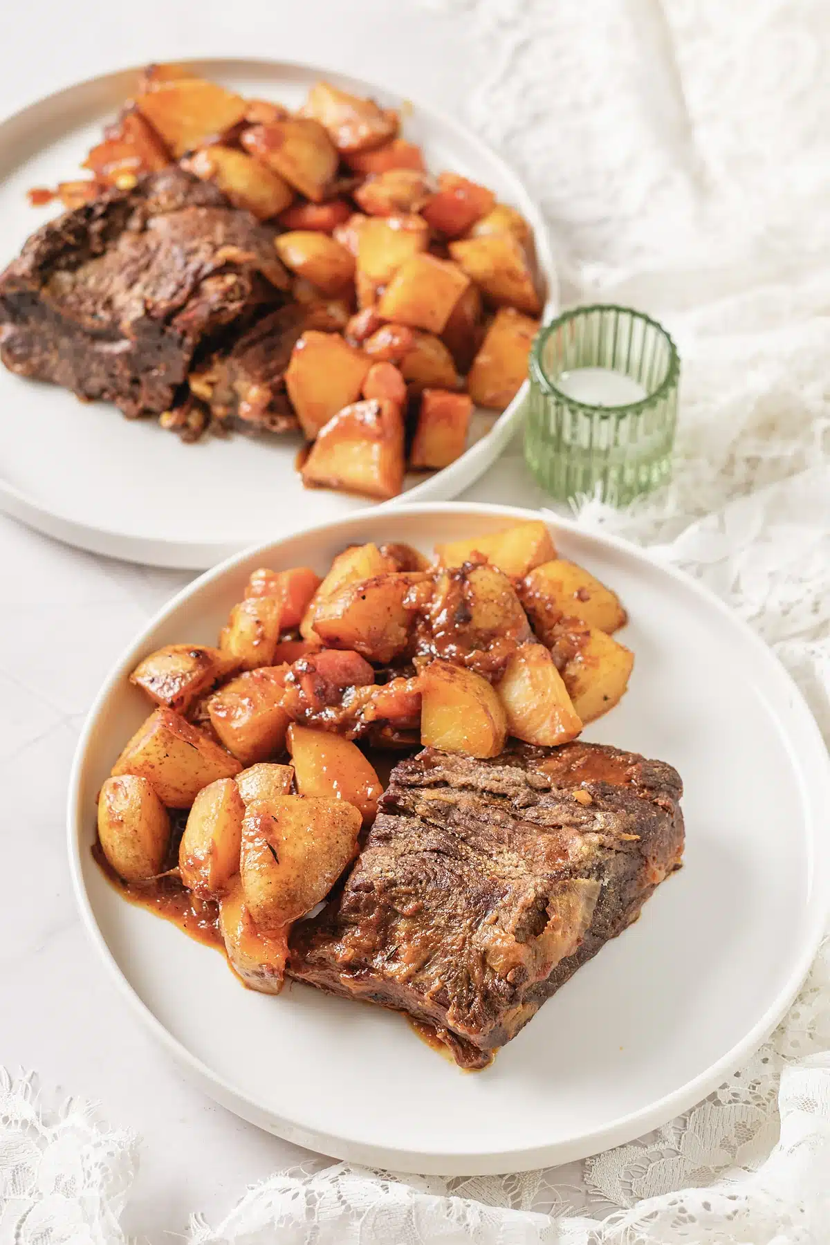 Classic pot roast served on two plates with potatoes and carrots