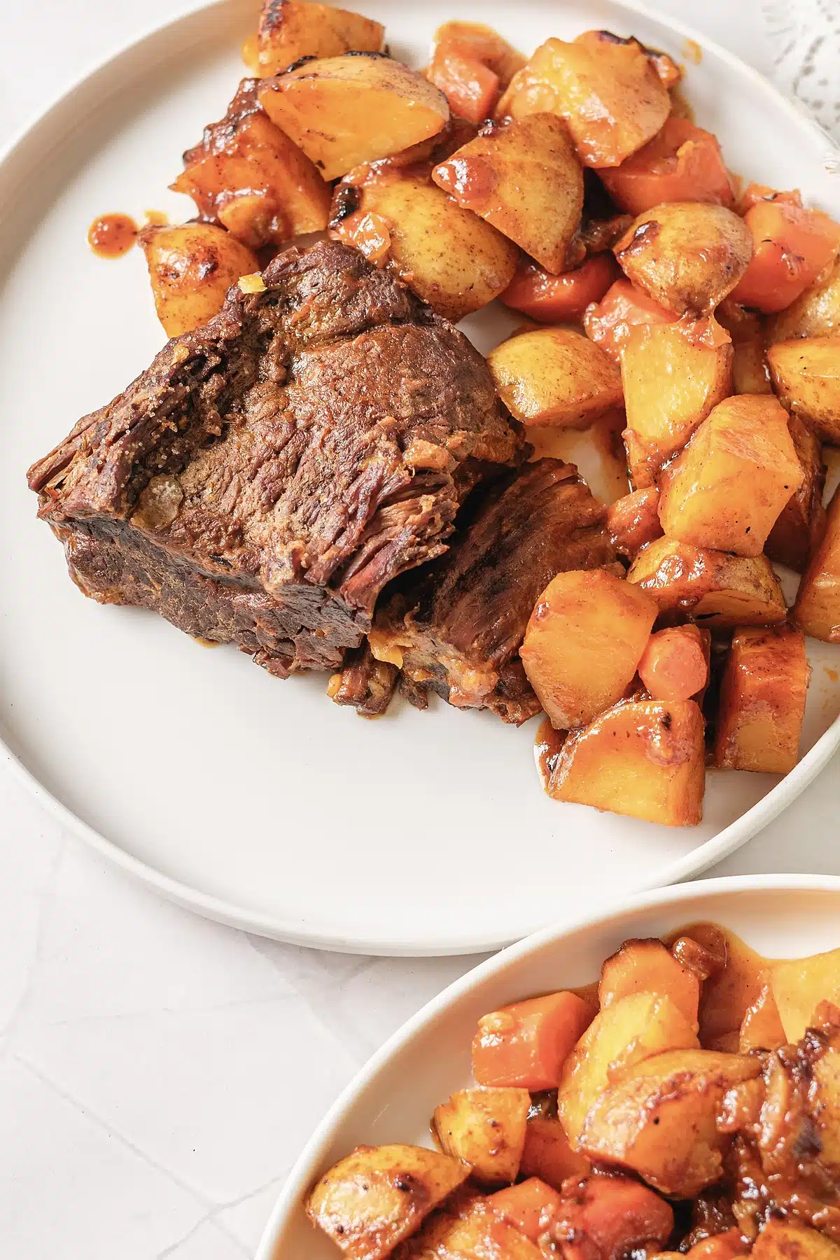 Close view of fork-tender beef and buttery vegetables on a wide platter