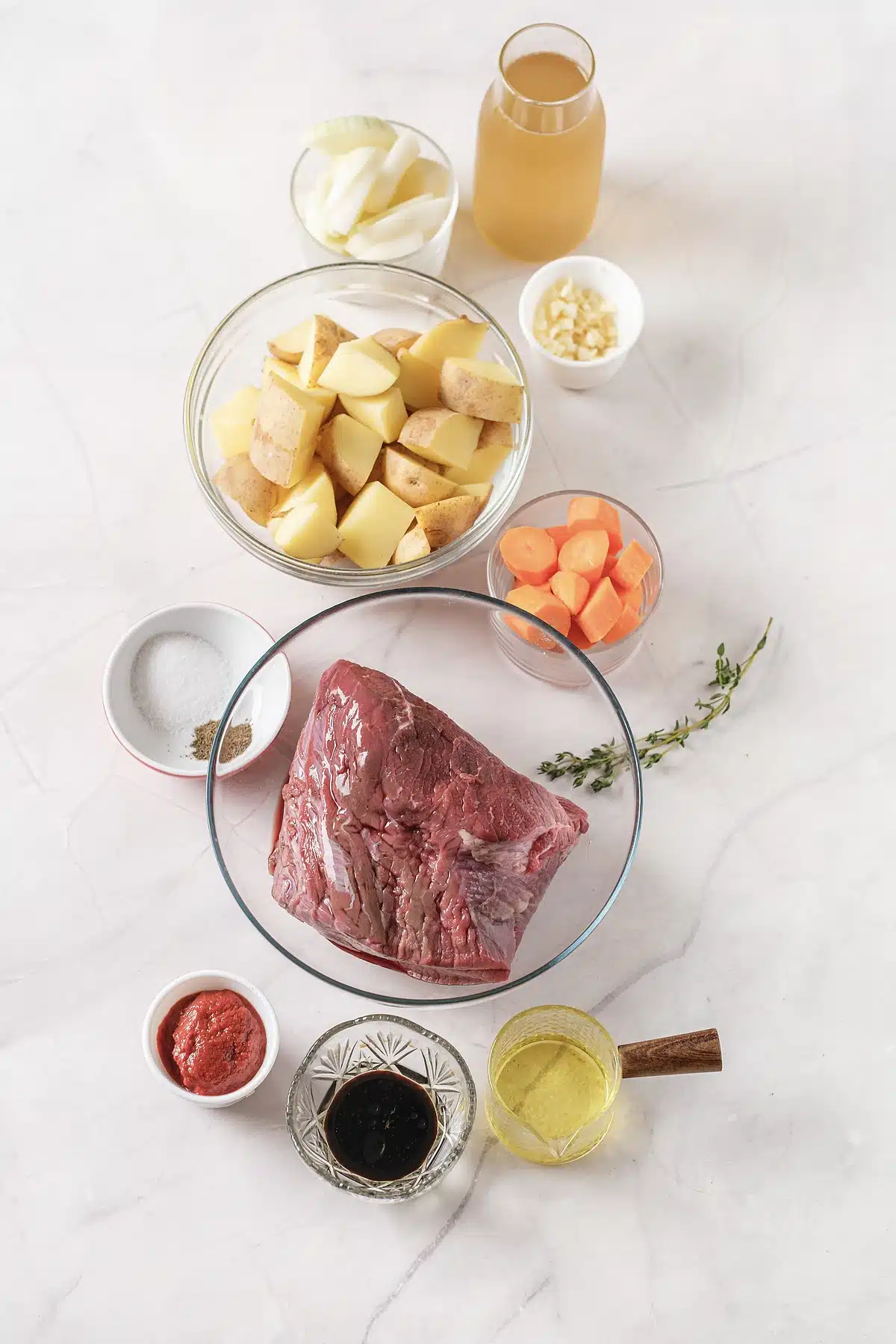 Chuck roast, potatoes, carrots, onion, tomato paste and red wine laid out in glass bowls