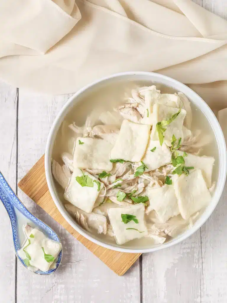 Cracker Barrel chicken and dumplings served in a white bowl on a wooden board