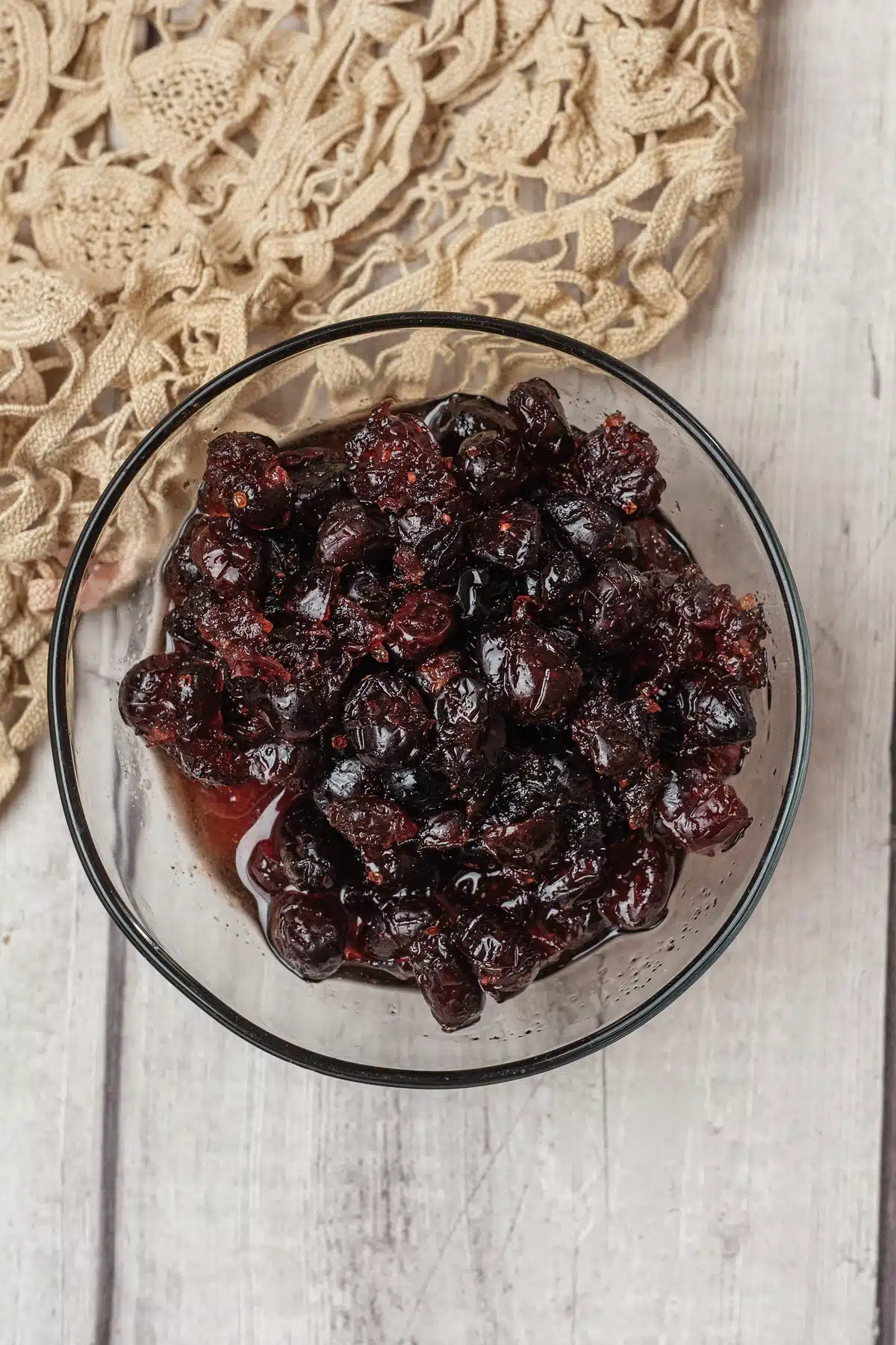 Cranberry sauce, dried cranberry version, in a glass bowl seen from directly above on a lace cloth