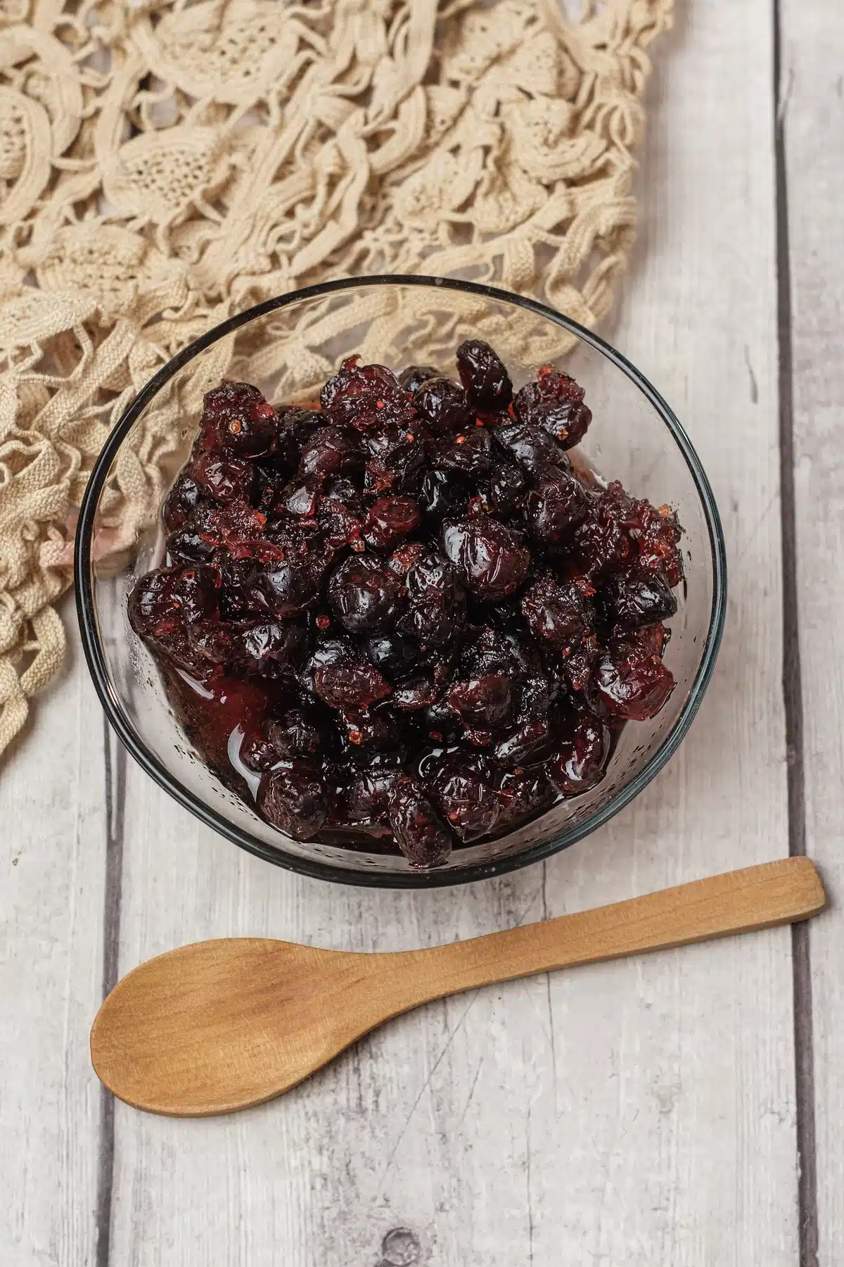 Cranberry sauce, dried cranberry version, in a glass bowl from above with a wooden spoon beside it