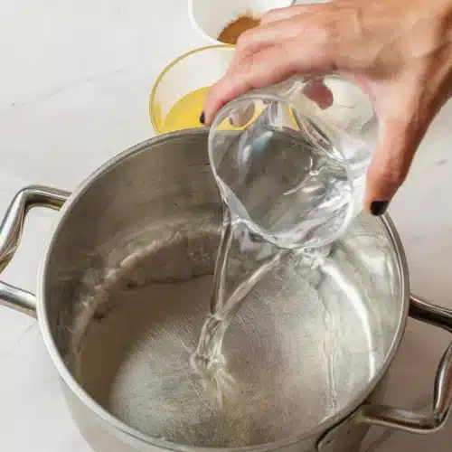 Water poured from a glass into a steel pot