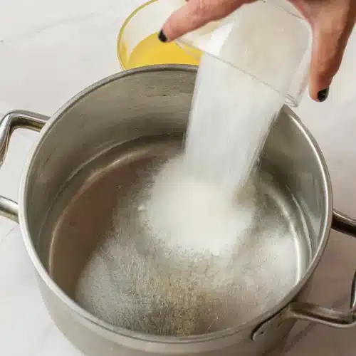 Granulated sugar tipped into the water in the pot