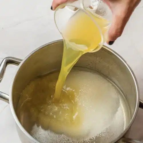 Orange juice poured into the sugar syrup in the pot