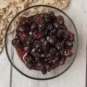 A single glass bowl of cranberry sauce, dried cranberry version, on a lace cloth