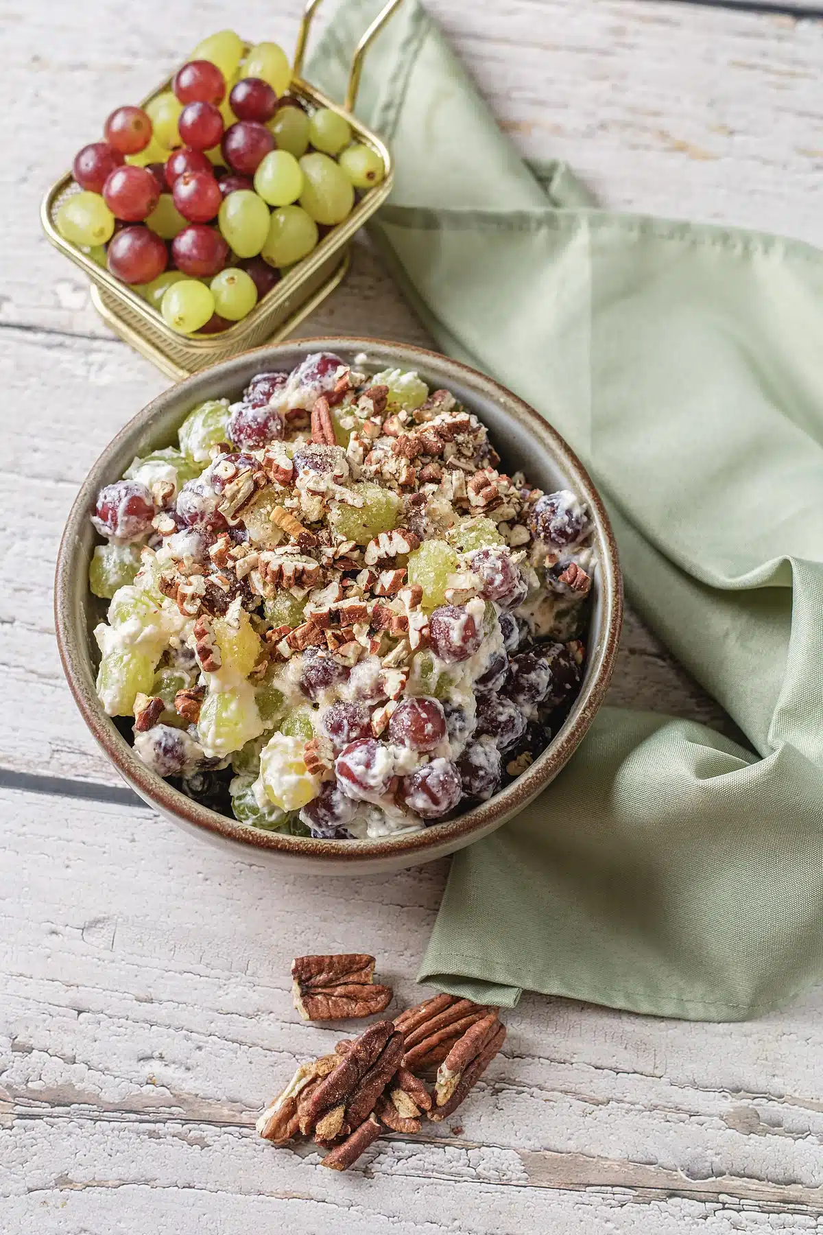 Grape salad served in a brown rimmed bowl with a green napkin alongside