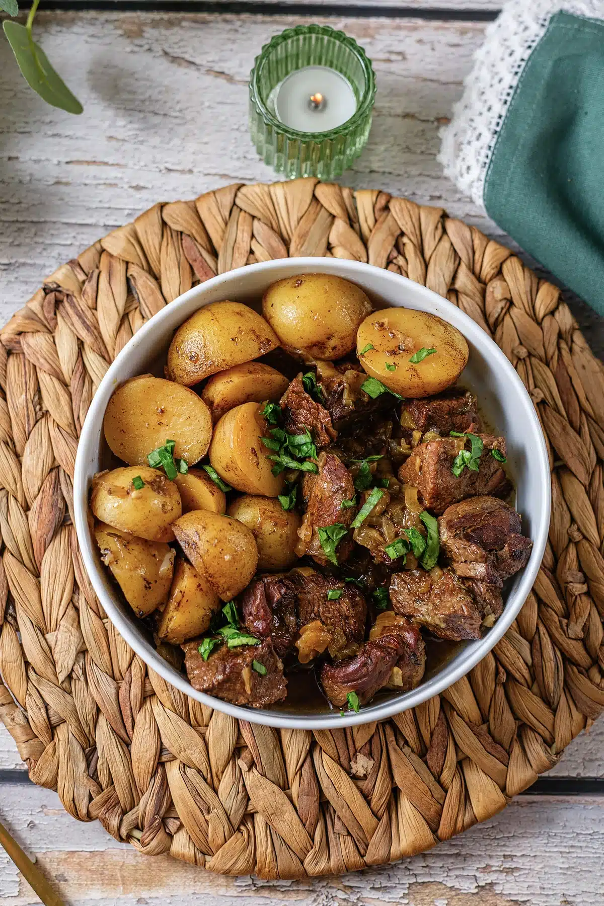 Crockpot steak and potatoes served in a white bowl on a woven placemat