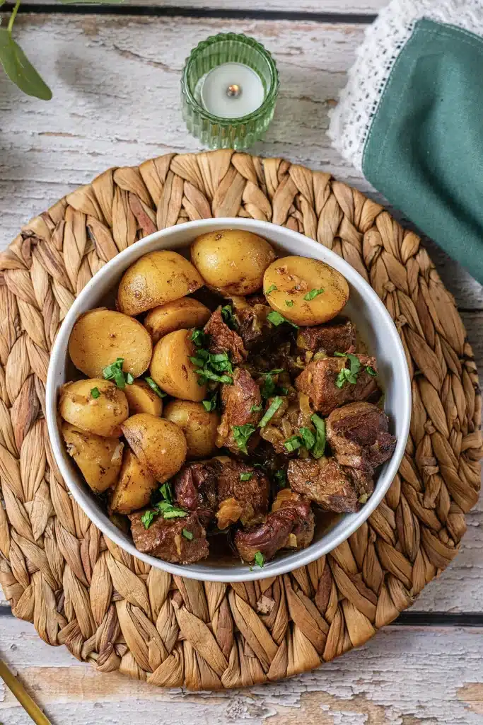 Crockpot steak and potatoes in a white bowl seen from directly above
