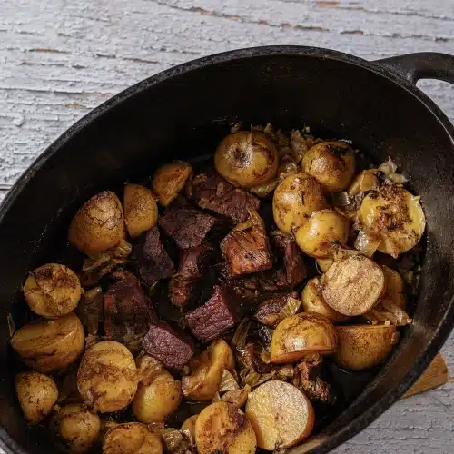 The finished contents of a dark pot, glossy and tender after a long cook