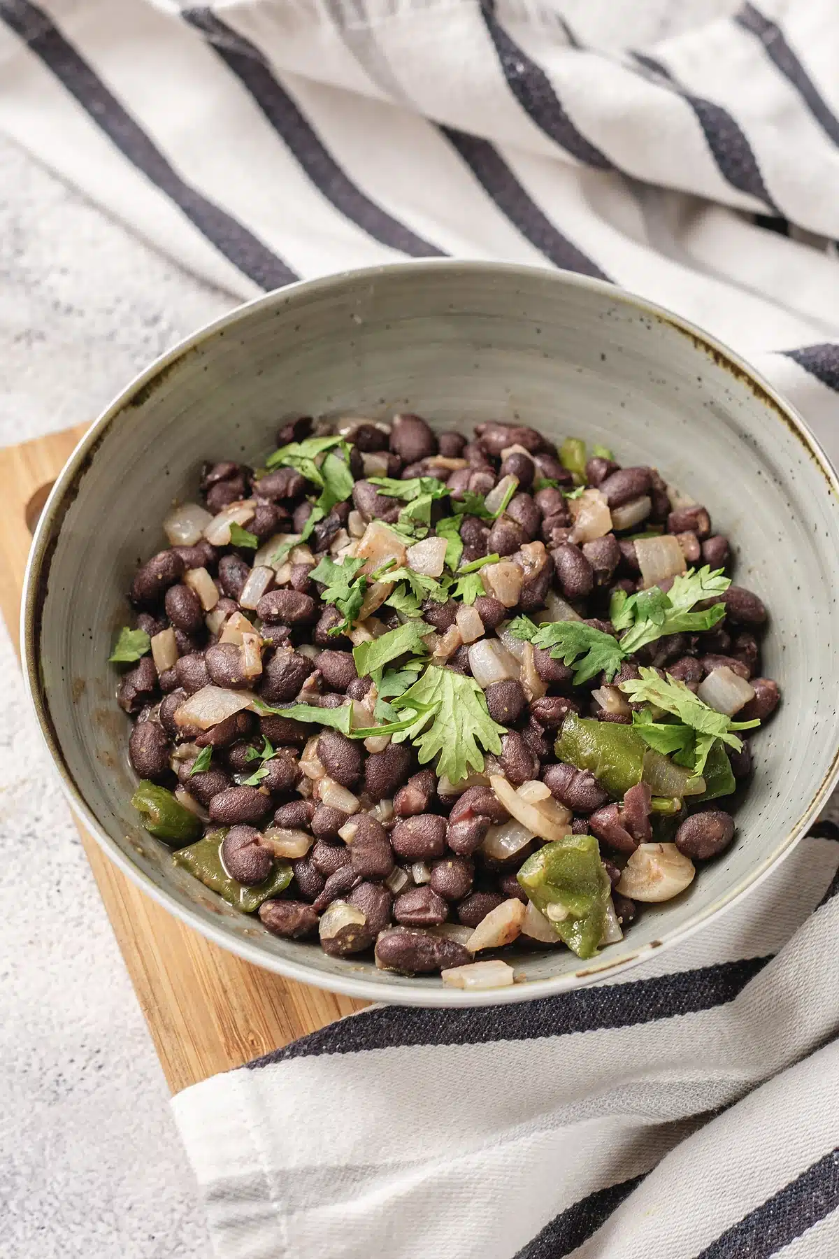 Cuban black beans in a speckled bowl with cilantro and green pepper