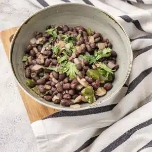 A single serving of cuban black beans in a speckled bowl with cilantro