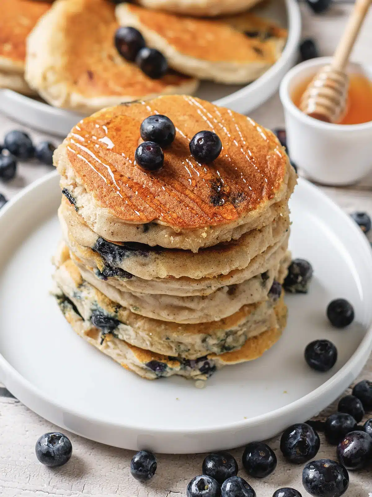 Fluffy blueberry pancakes stacked high and drizzled with honey