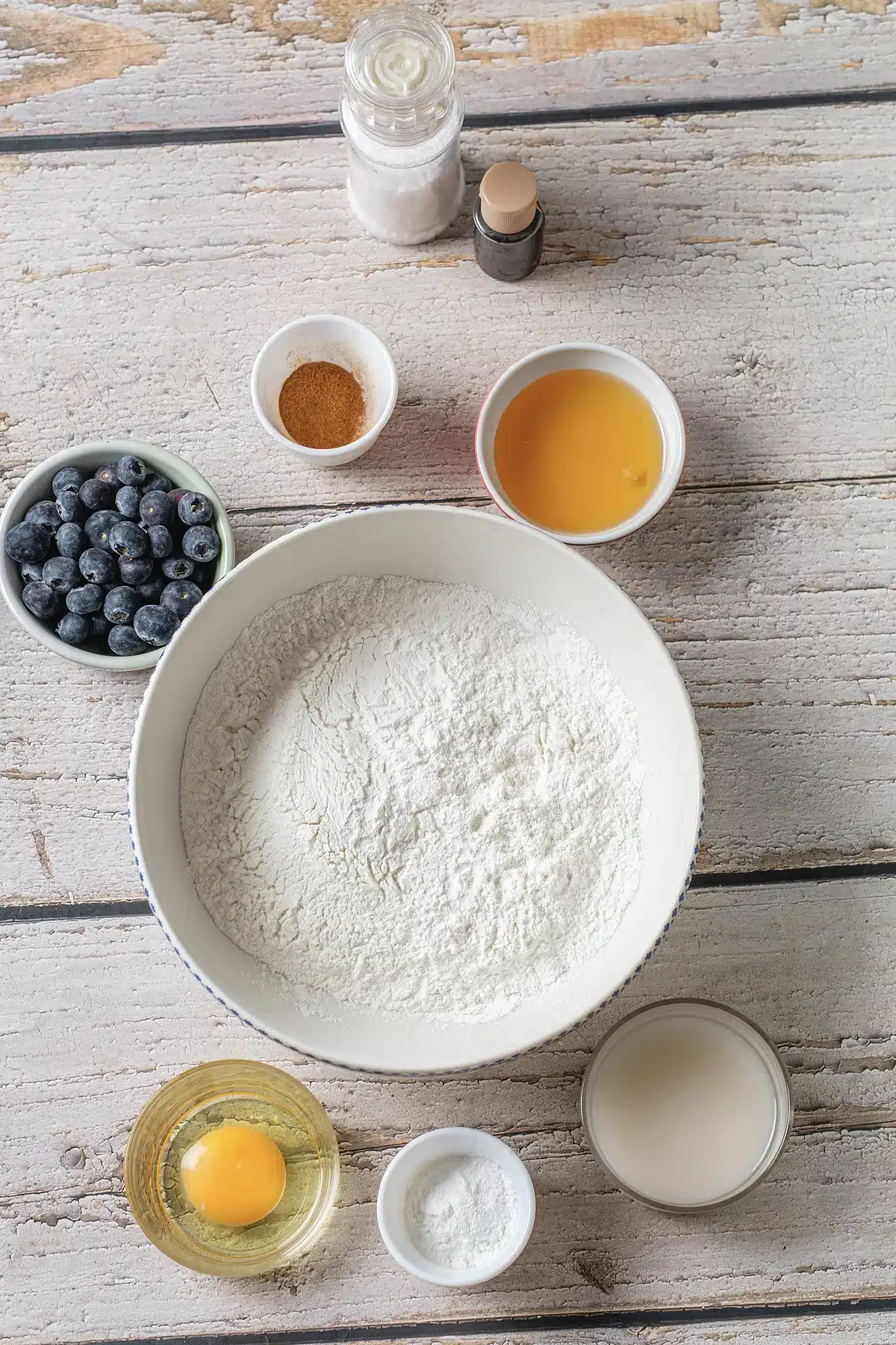 Flour, milk, egg, honey, salt, cinnamon and fresh berries laid out in bowls