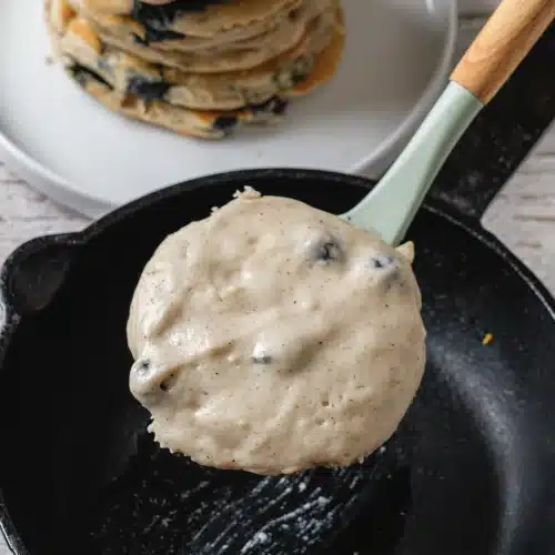 A spatula lifting a soft round of batter above the pan