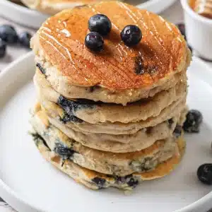 A single stack of fluffy blueberry pancakes on a small white plate