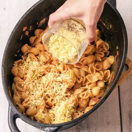 Grated Parmesan tipped from a bowl over the shells in the skillet