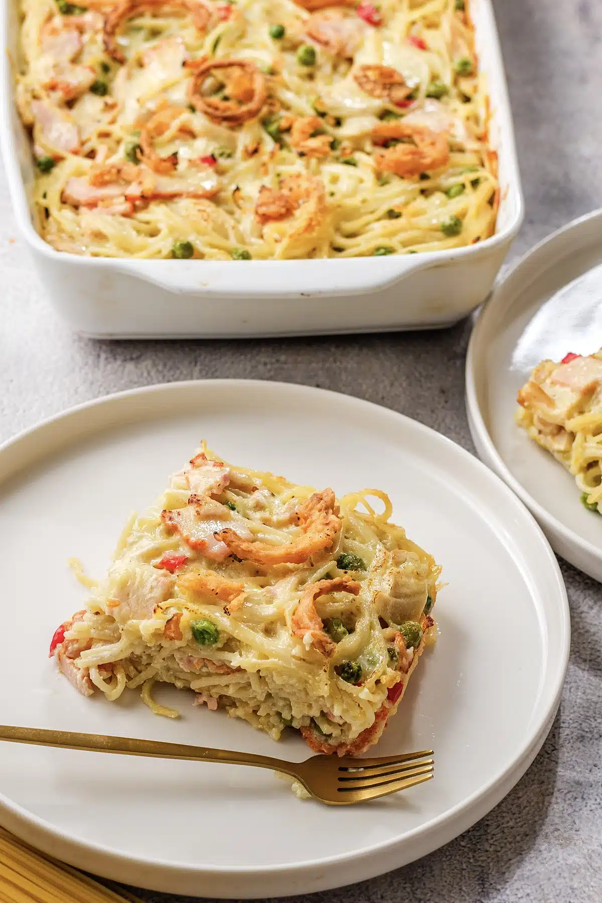 Ham tetrazzini plated in a square with the baking dish behind it