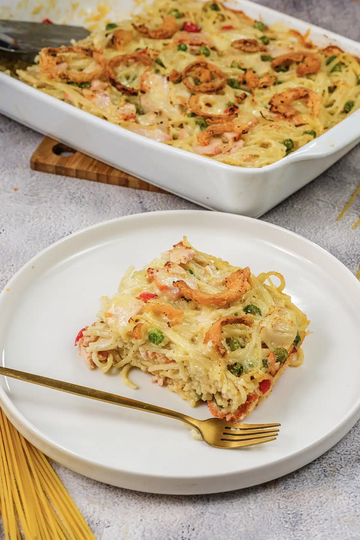 Ham tetrazzini in its dish on a wooden board with a plated square alongside