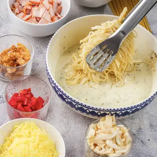 Cooked spaghetti lifted into a bowl of warm cream sauce