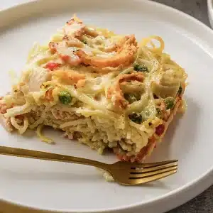 A single square of ham tetrazzini on a white plate with two gold forks
