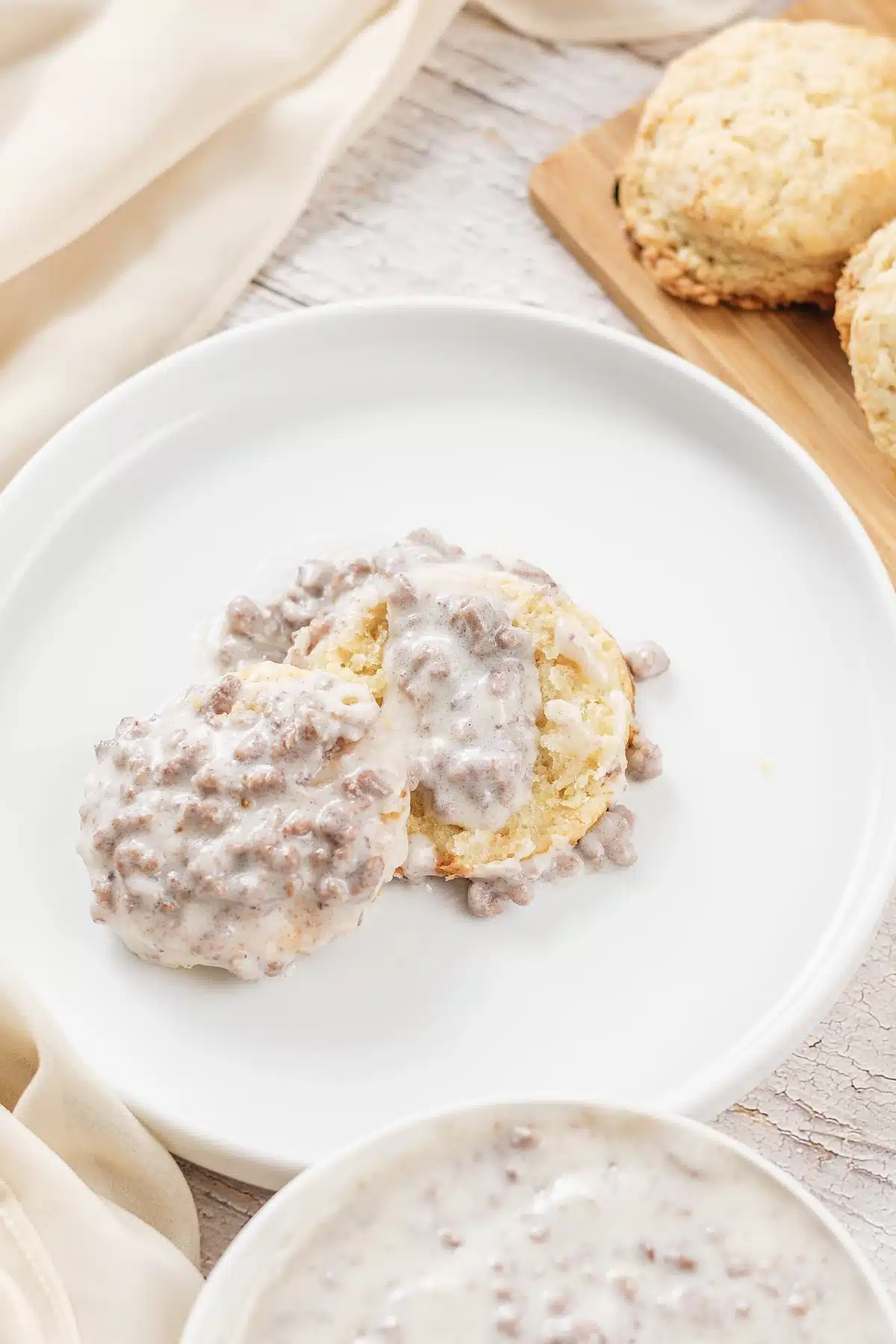 A close view of thick peppered white sauce over a halved biscuit