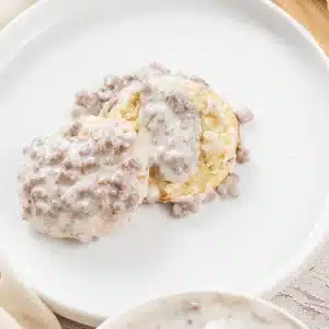 A single plate of sausage gravy over a split biscuit