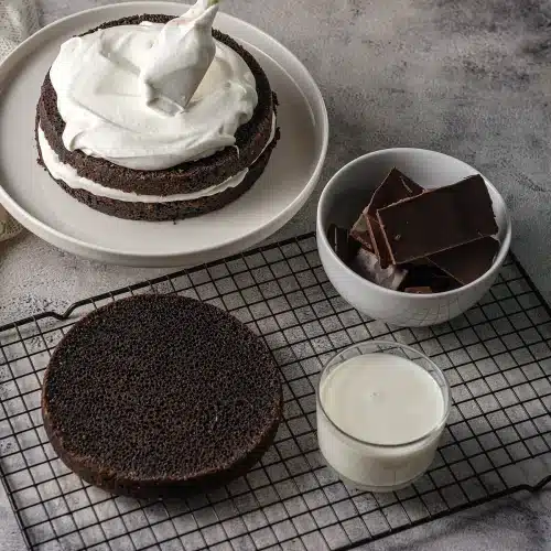 A spatula smoothing white filling across the top of a stacked round
