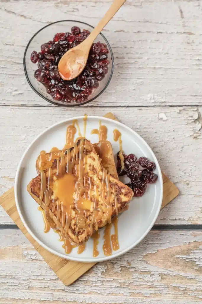 IHOP French toast stack with caramel drizzle and dried cranberries on a white plate, seen from directly above