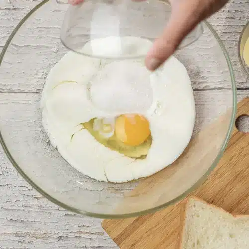 Sugar tipped into the bowl of eggs and milk