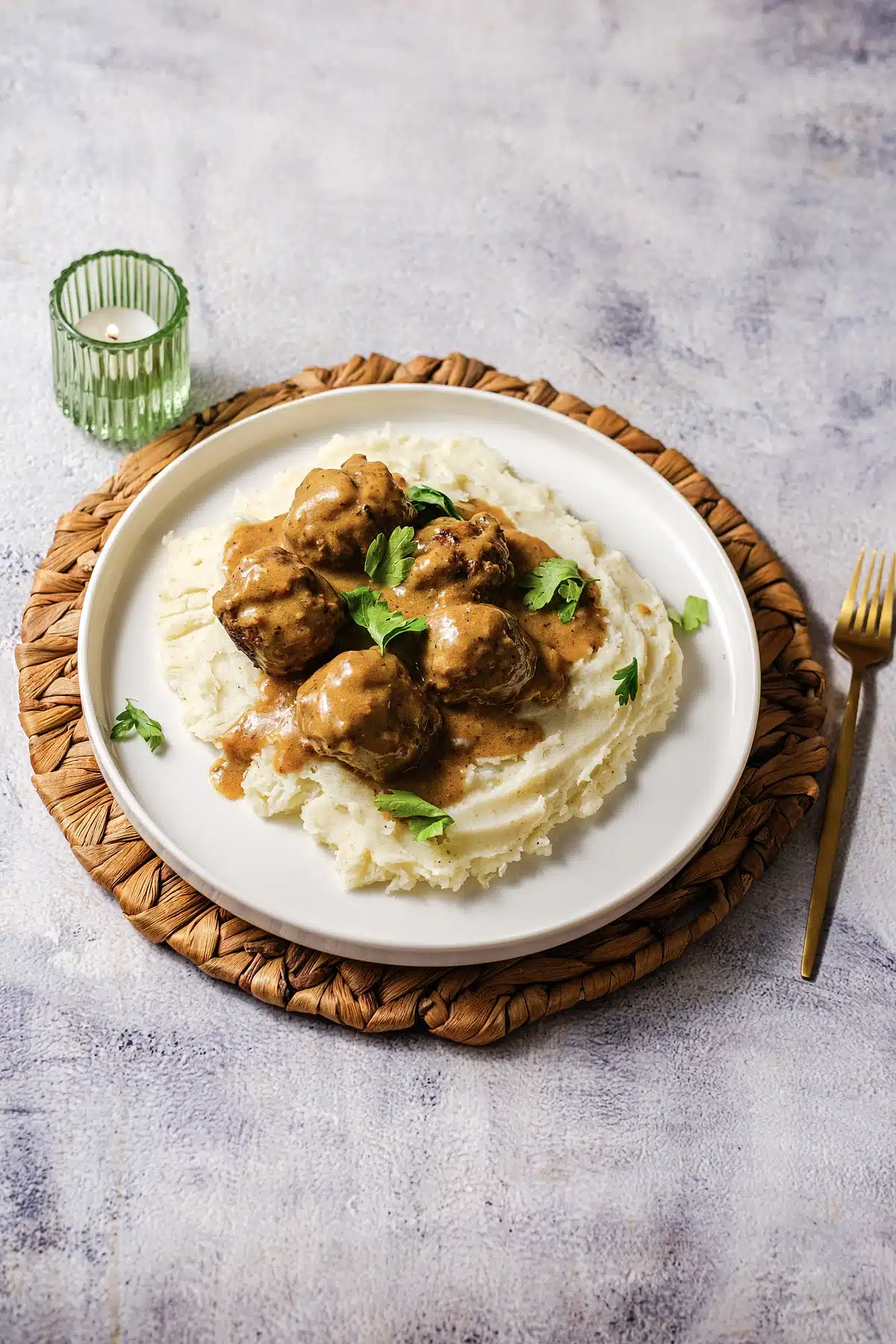 A single plate of gravy-covered meatballs over mashed potato, seen from above