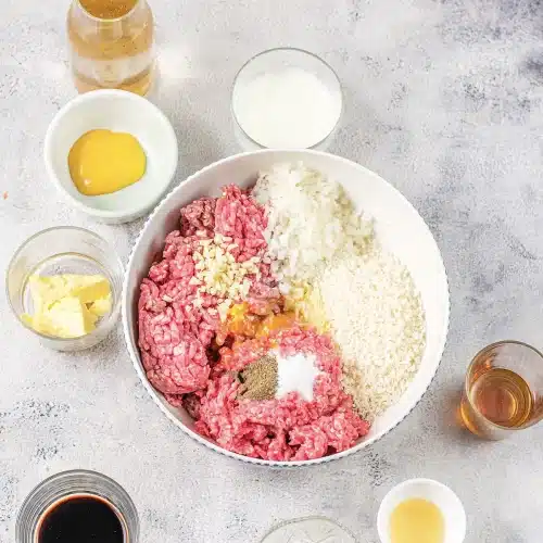 Ground beef and pork in a bowl with crumbs, onion and an egg yolk