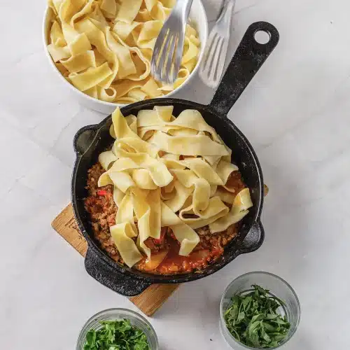 The pasta piled on top of the sauce before it is tossed