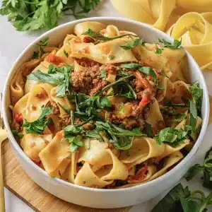 A single bowl of Italian drunken noodles topped with torn basil