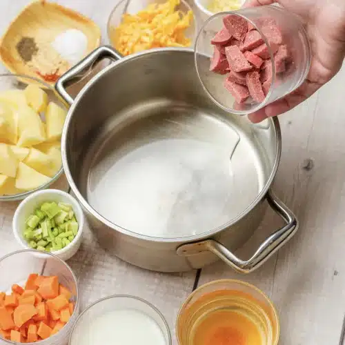 Diced kielbasa tipped from a bowl into a steel pot